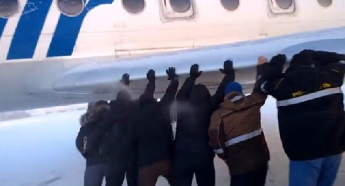 VIDEO / N-ai mai văzut aşa ceva cu siguranţă! Pasageri ruşi, nevoiţi să împingă un avion al cărui tren de aterizare îngheţase