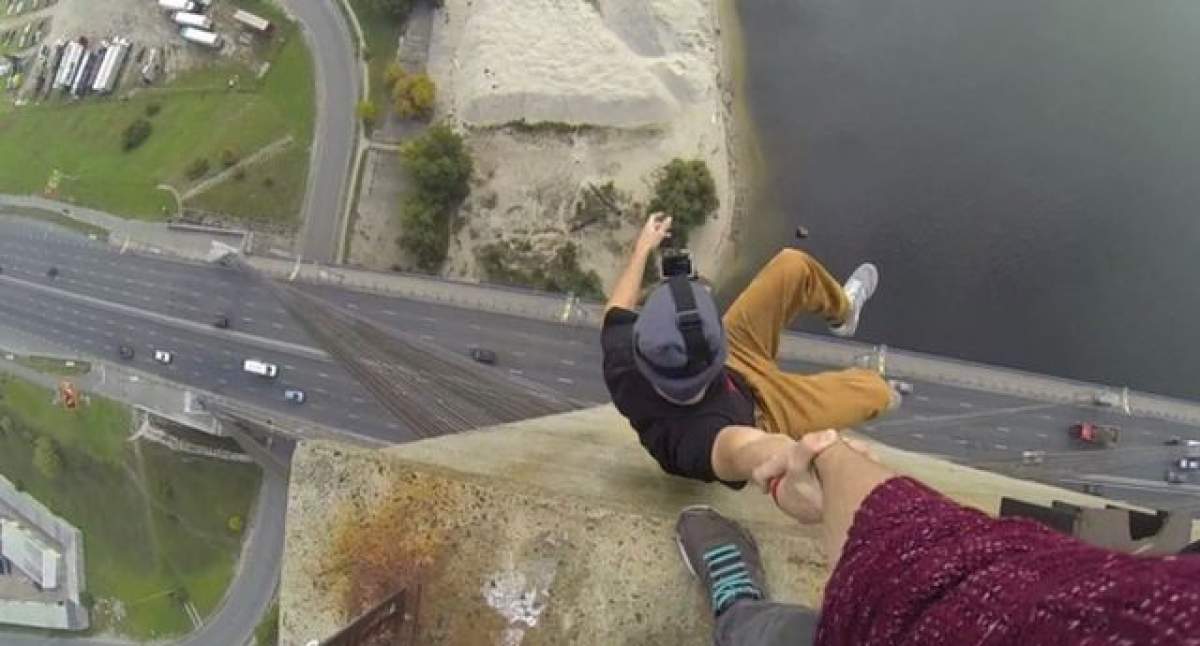 VIDEO Ce nebun! S-a agăţat de mâna prietenului său, la peste 100 de metri înălţime. O să ţi se facă rău când o să vezi continuarea