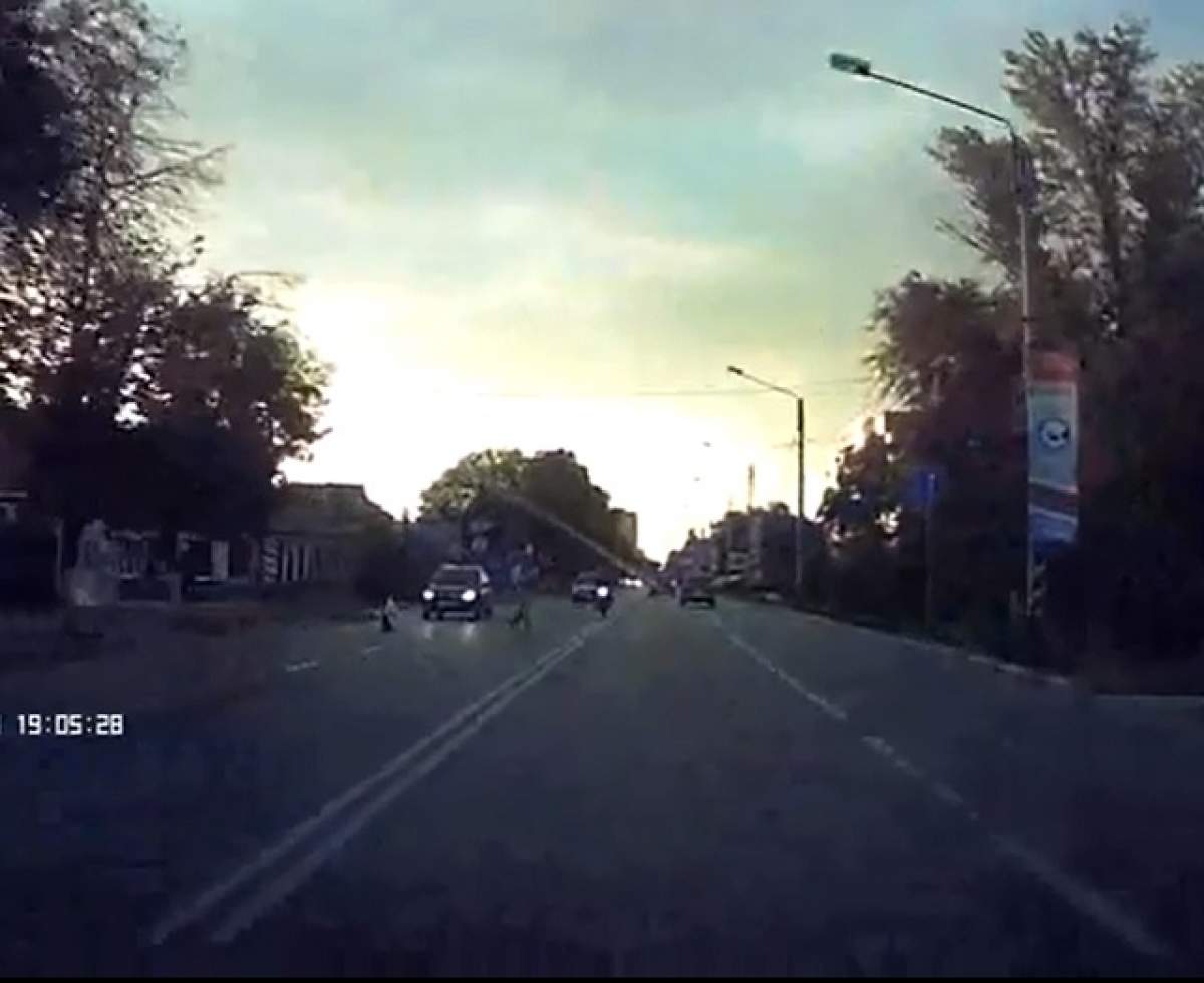 VIDEO ŞOCANT / Ce inconştient! A fost izbit de o motocicletă după ce a trecut strada ilegal, cu copilul în braţe