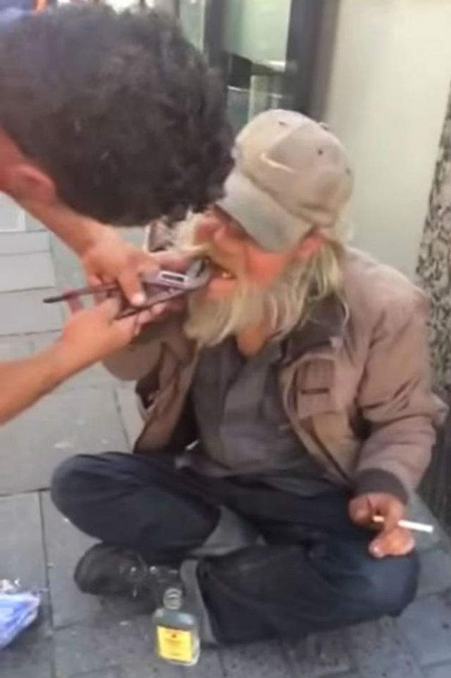VIDEO / Scene ca-n Evul Mediu! Un om fără adăpost, filmat în timp ce un bărbat îi scoate un dinte cu un cleşte, în plină stradă