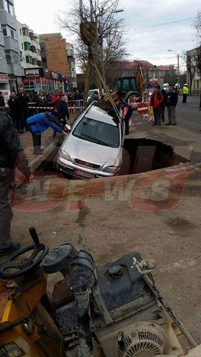 FOTO / Imagini incredibile în centrul oraşului! S-a trezit cu maşina într-un crater imens, după ce strada s-a surpat