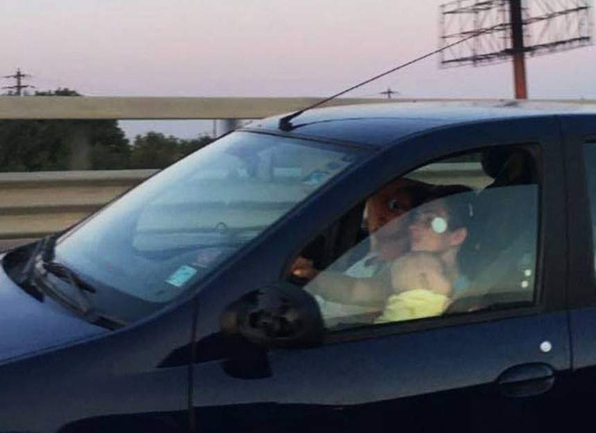 FOTO / O femeie a fost surprinsă în timp ce conducea cu bebeluşul în braţe. Gestul poate fi mortal! Fotografiile au ajuns virale