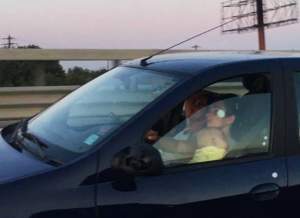 FOTO / O femeie a fost surprinsă în timp ce conducea cu bebeluşul în braţe. Gestul poate fi mortal! Fotografiile au ajuns virale