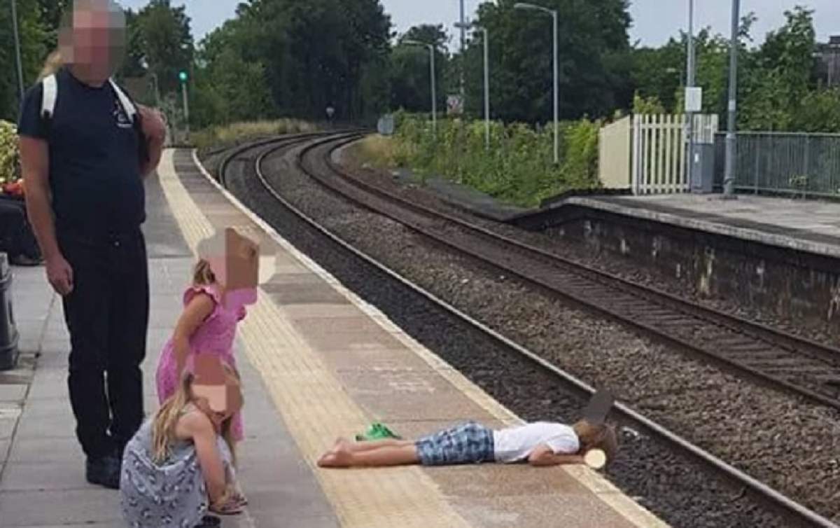FOTO / Un copil stătea întins lângă calea ferată, fiind la un pas de o tragedie. Cum se apără tatăl