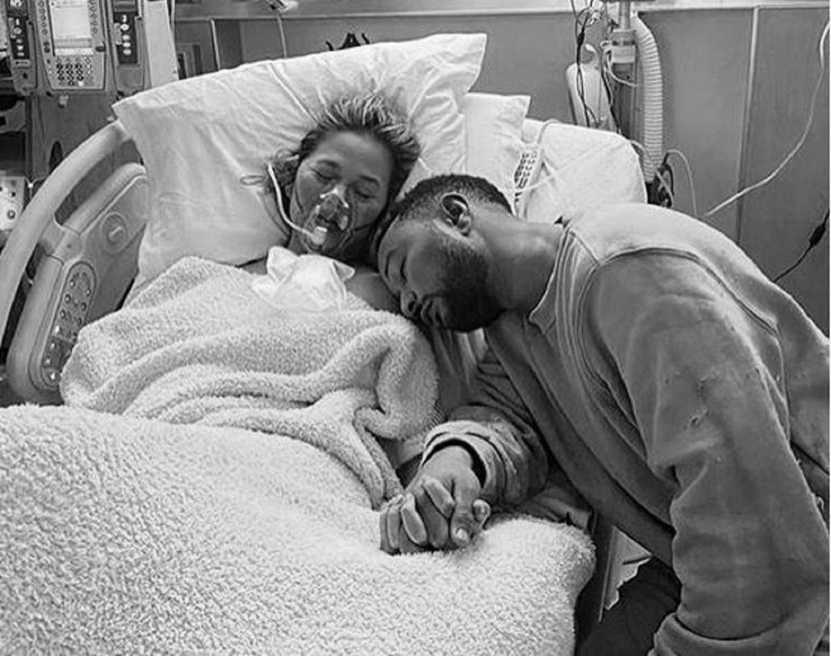 Chirssy Teigen și John Legend se țin de mână pe patul spitalului.