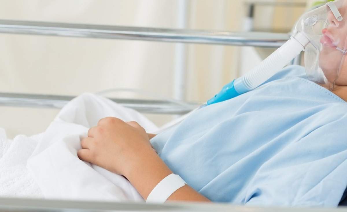 Copil bolnav pe patul de spital cu mască de oxigen