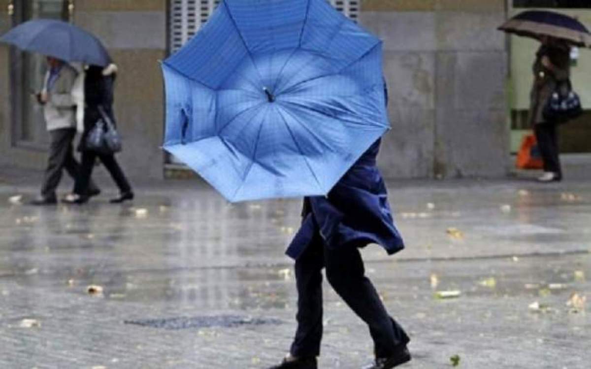 Femeie cu umbrela zburată de vânt