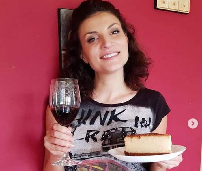 Ioana Ginghină ține în mâini tortul și un pahar de vin. Artista poartă un tricou negru.