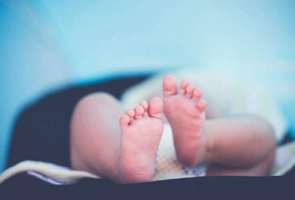 Picioarele unui bebeluș. Acesta este înfășurat în material alb.