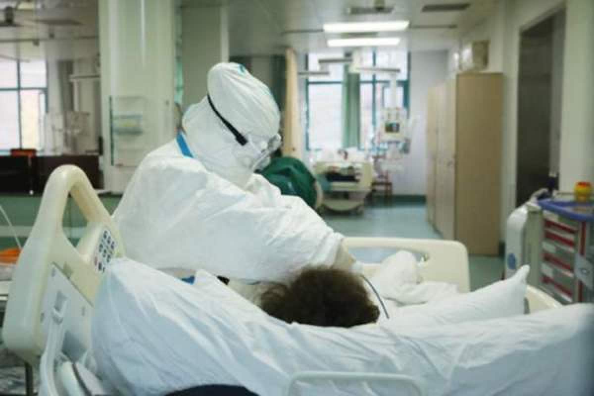 Medic care îngrijește un pacient, aflat pe patul de spital