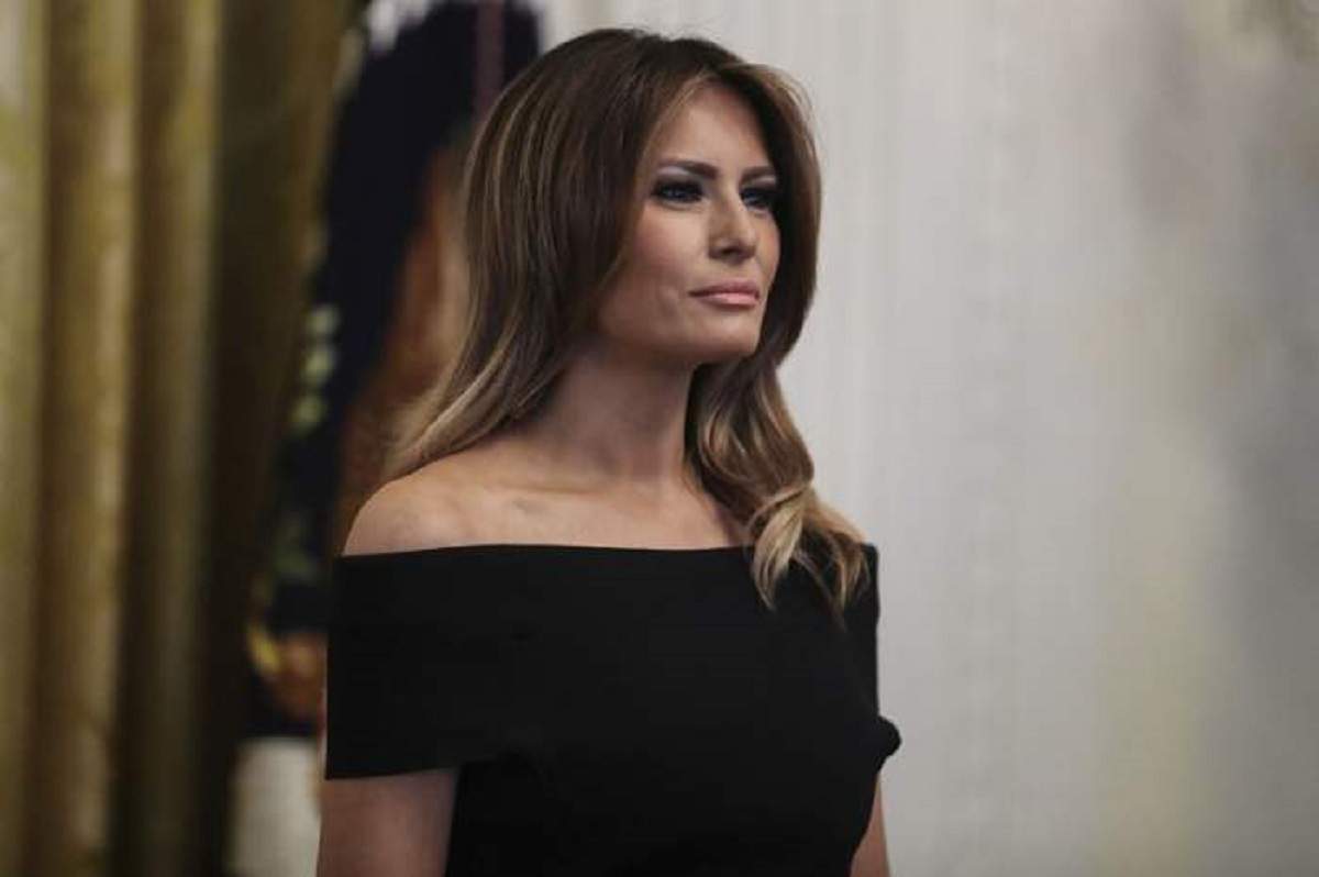 Melania Trump poarta o rochie neagra, fara umeri si parul desprins pe spate