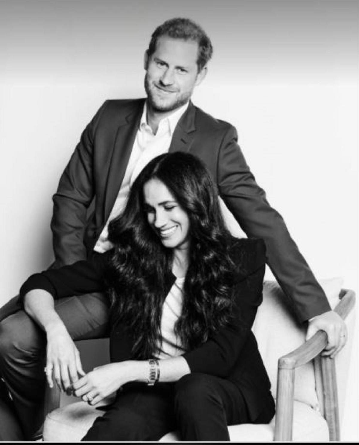 Meghan Markle sta pe scaun, langa Printul Harry