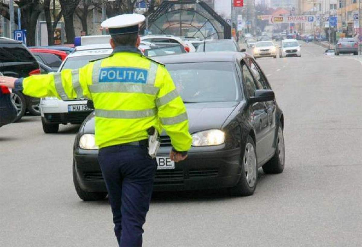 Un polițist de frontieră îi face semn unui șofer. Acesta este așezat cu spatele.
