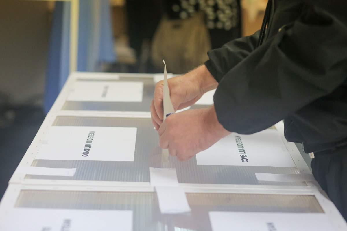 O persoana introduce un buletin de vot intr-o urna in timpul alegerilor locale, duminica, 27 septembrie 2020, in Timisoara