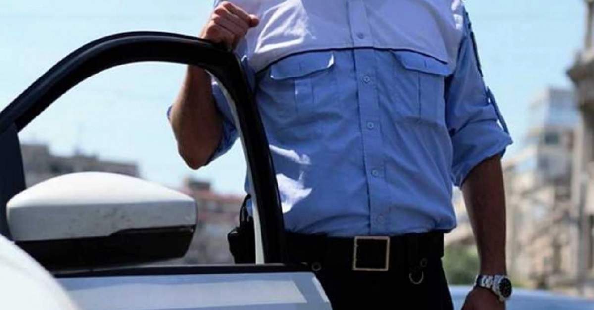 Bust polițist în cămașă lângă o portieră deschisă
