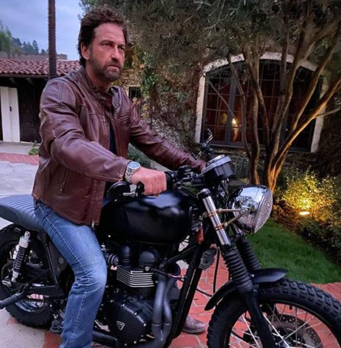 Gerard Butler este pe o motocicleta neagra, poarta jacheta de piele maro