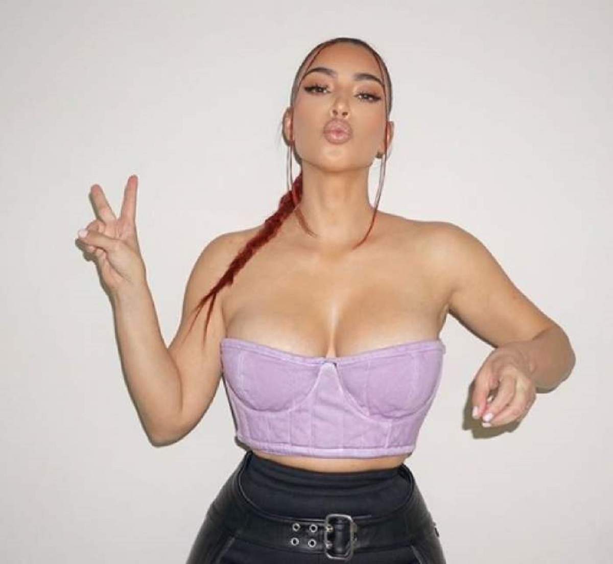 Kim Kardashian poarta un corset mov, are parul prins si arata semnul pacii