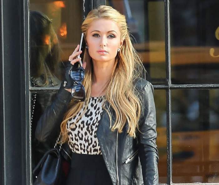 Paris Hilton vorbeste la telefon, are jacheta de piele si parul desprins