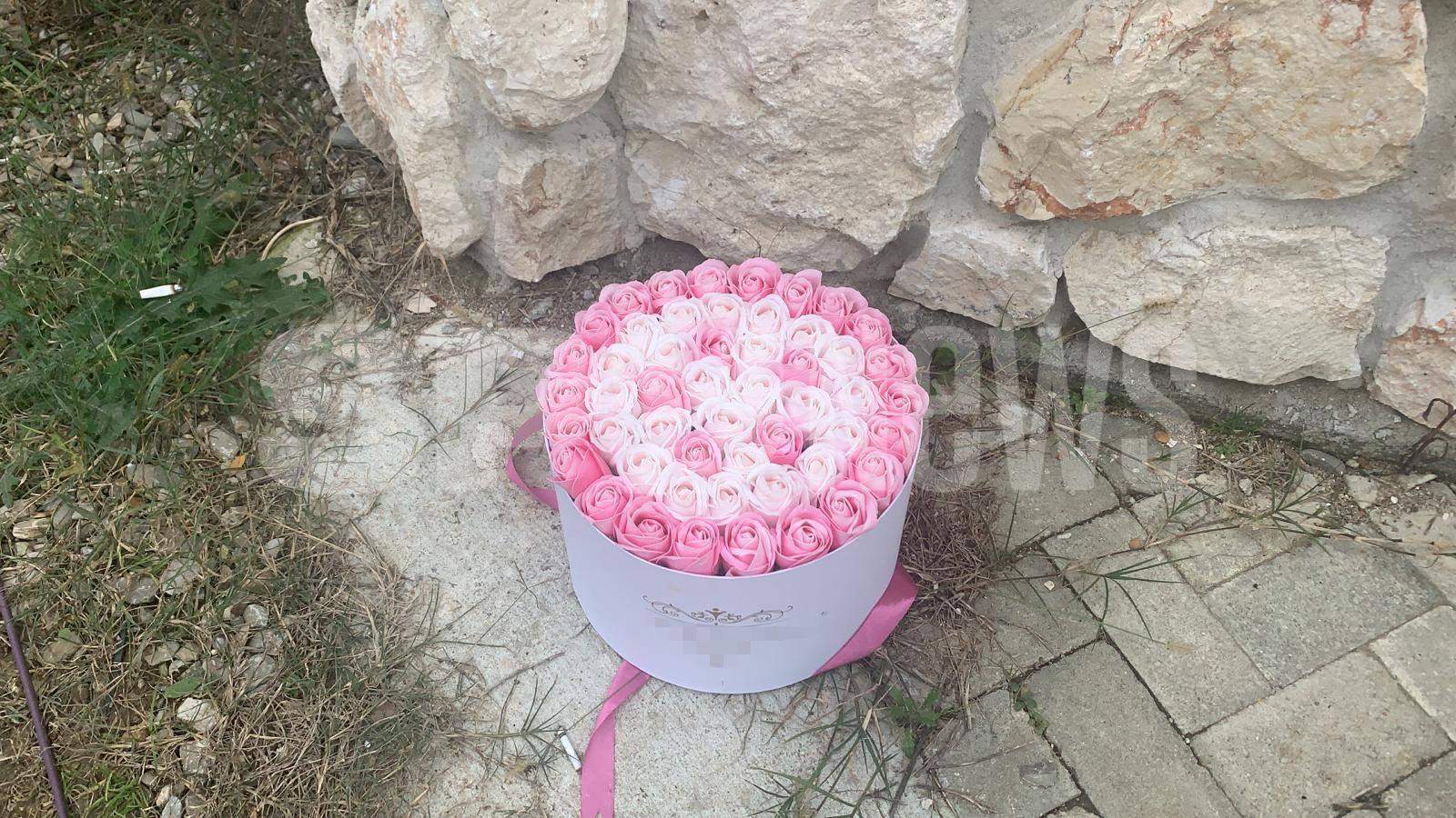 Poarta lui Alex Bodi. Lângă gunoi este un buchet de flori roz.