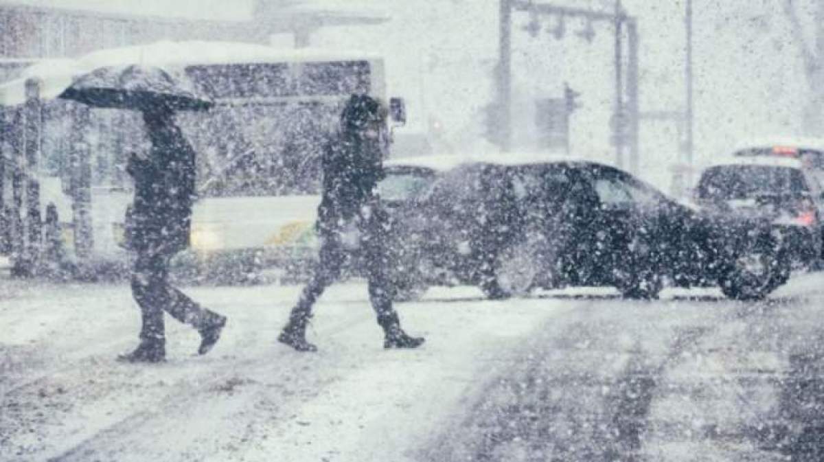 Mai multe persoane care se află în zăpadă în stradă