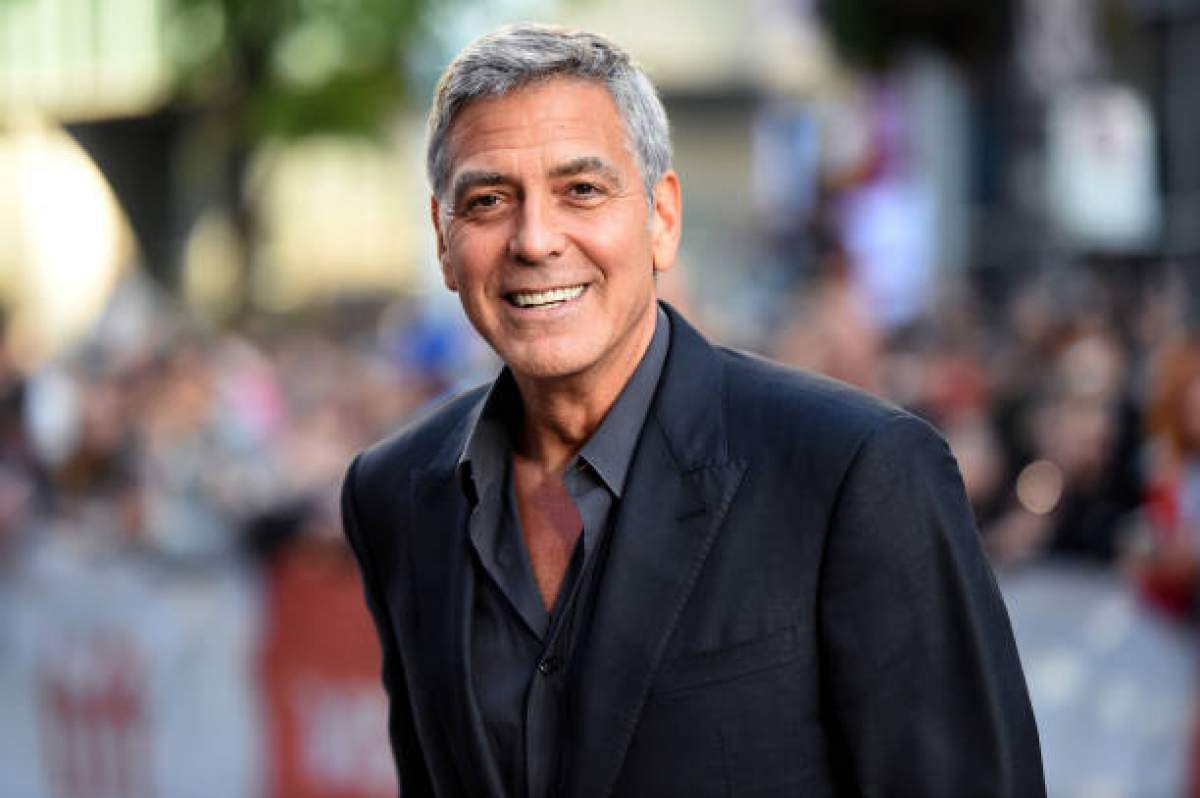 George Clooney poarta un costuim negru si zambeste larg