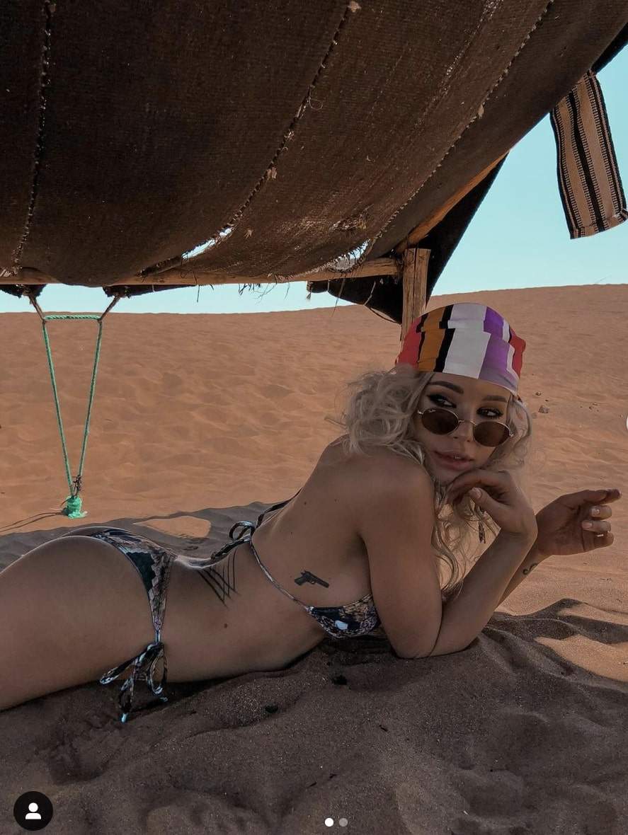 Carmen Grebenisan este in costum de baie si bocanci, intinsa pe nisip in desert