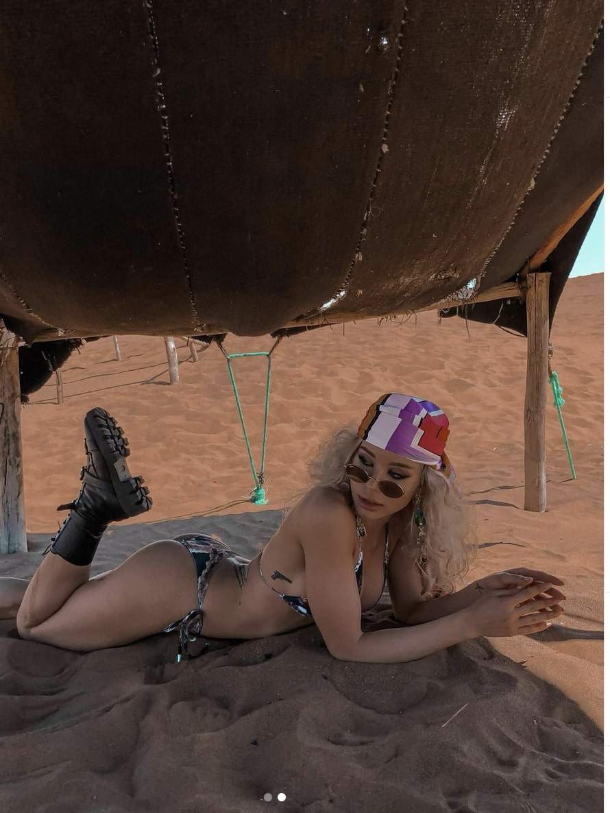 Carmen Grebenisan este in costum de baie si bocanci, intinsa pe nisip in desert