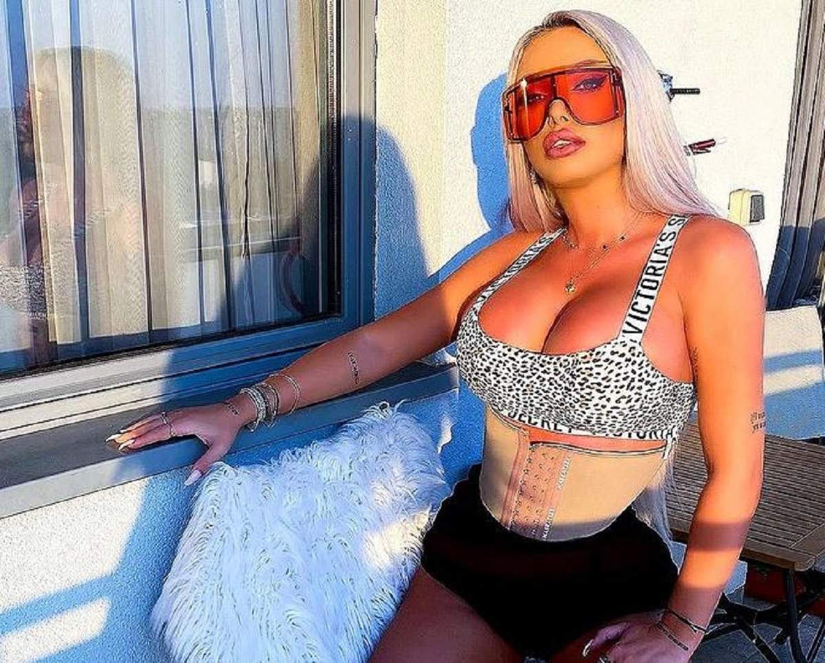 Loredana Chivu e îmbrăcată cu o bustieră albă, cu animal print și o pereche de pantaloni scurți, negri. Vedeta poartă ochelari de soare oranj.