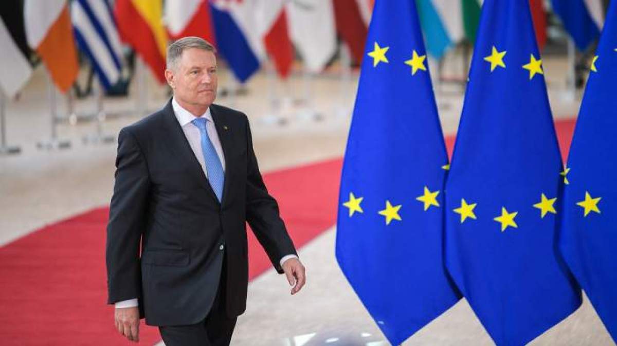 Klaus Iohannis, fotografiat zâmbitor lângă steagurile UE