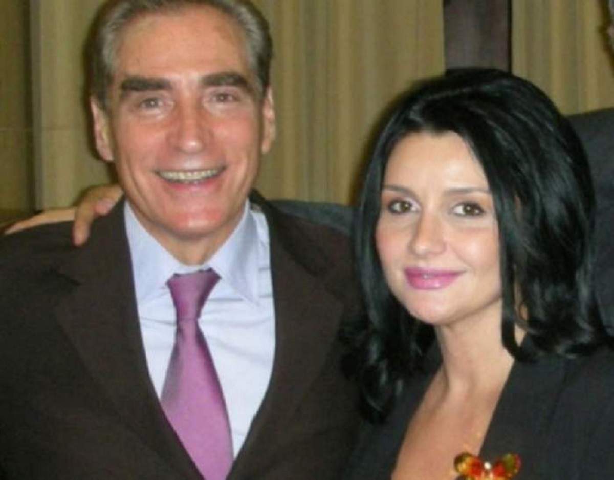 Petre Roman și Silvia Chifiriuc la un eveniment. El poartă un costum maroniu, cu cămașă albă și cravată mov, iar ea un sacou negru.