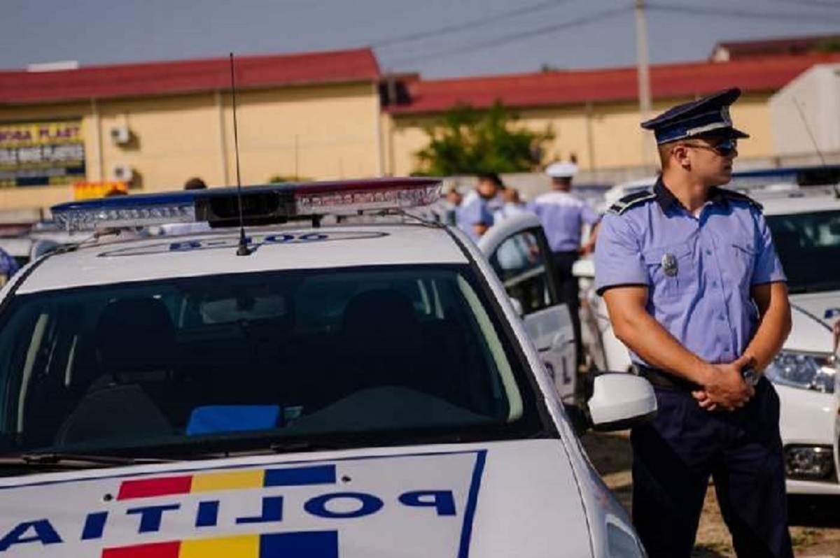 Imagine cu un politist langa masina de politie
