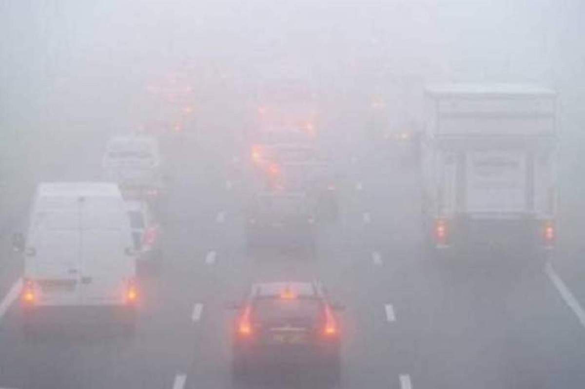 Niște mașini care circulă prin ceață, pe șosea