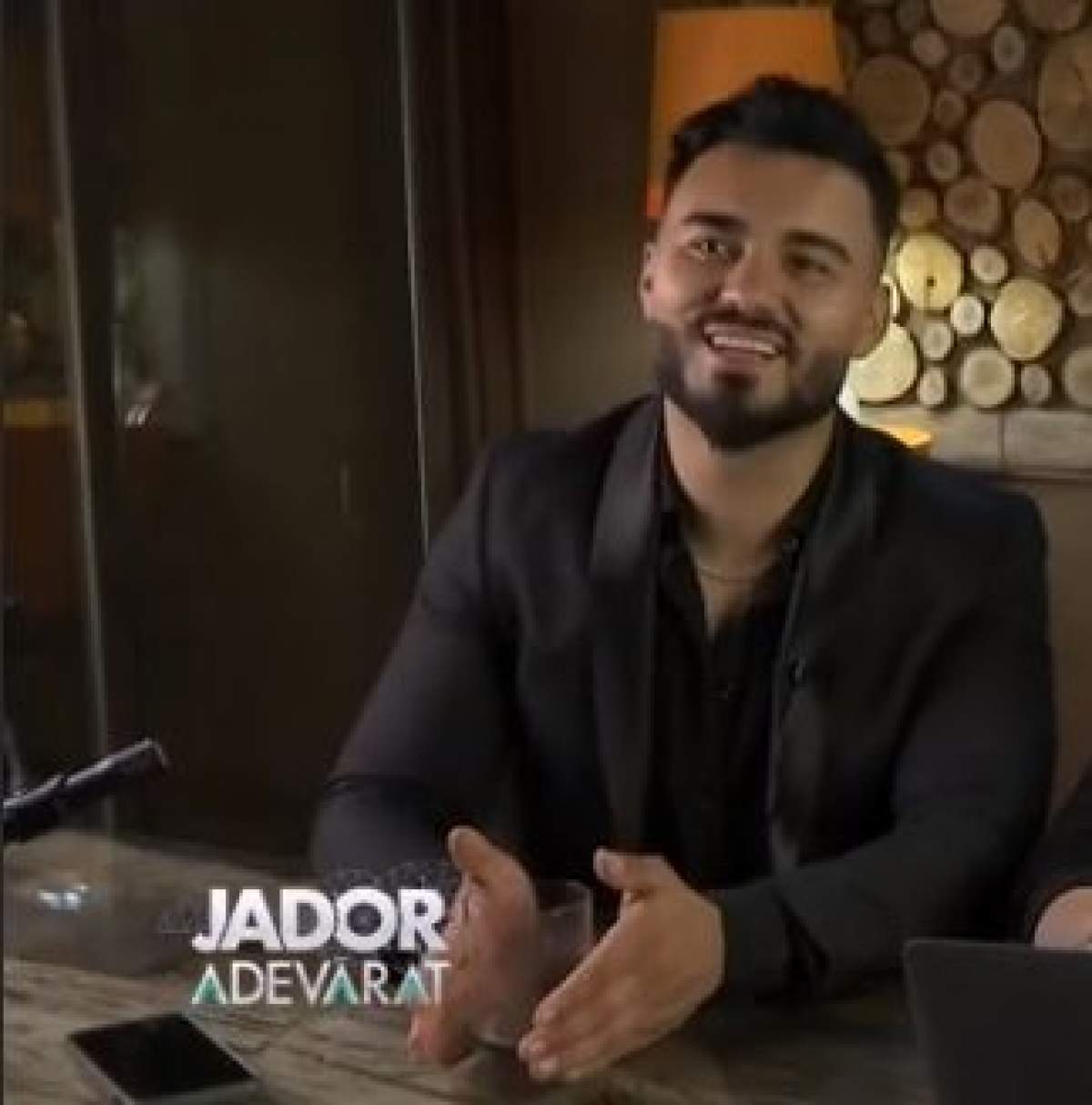 Jador, surprins în dreptul unei filmări, zâmbitor, în costum negru