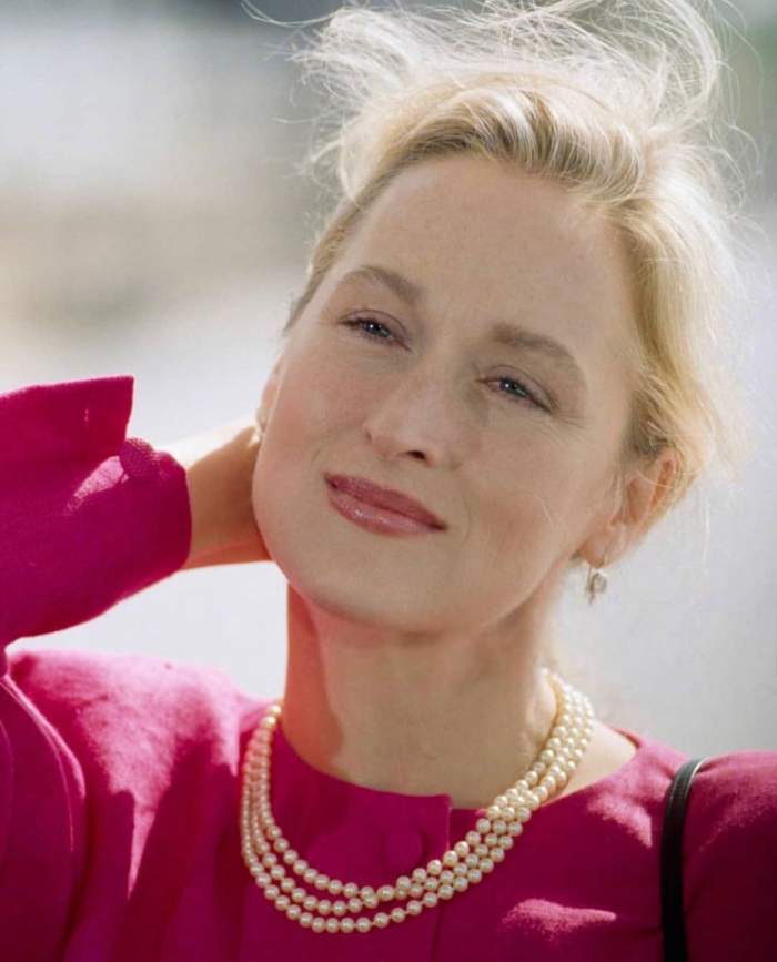 Meryl Streep poarta o rochie roz, un colier din perle si are parul prins