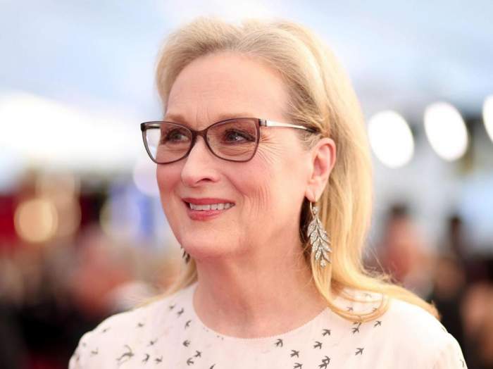 Meryl Streep este pe covorul rosu, poarta ochelari si o rochie alba