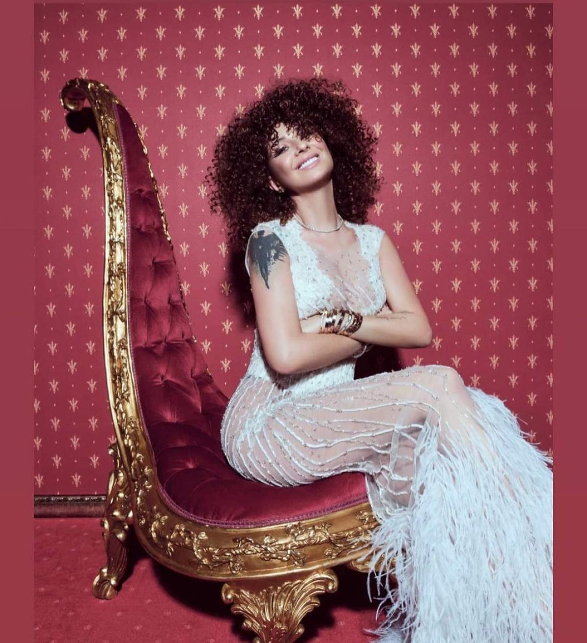 Anamaria Prodan s-a fotografiat stând pe un scaun, într-o rochie albă și cu o coafură afro