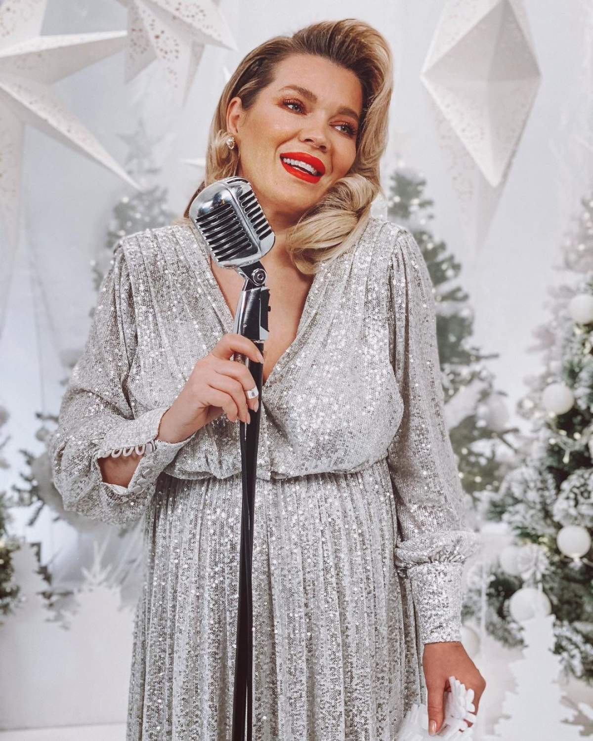 Gina Pistol poarta o rochie argintie, are parul aranjat si canta
