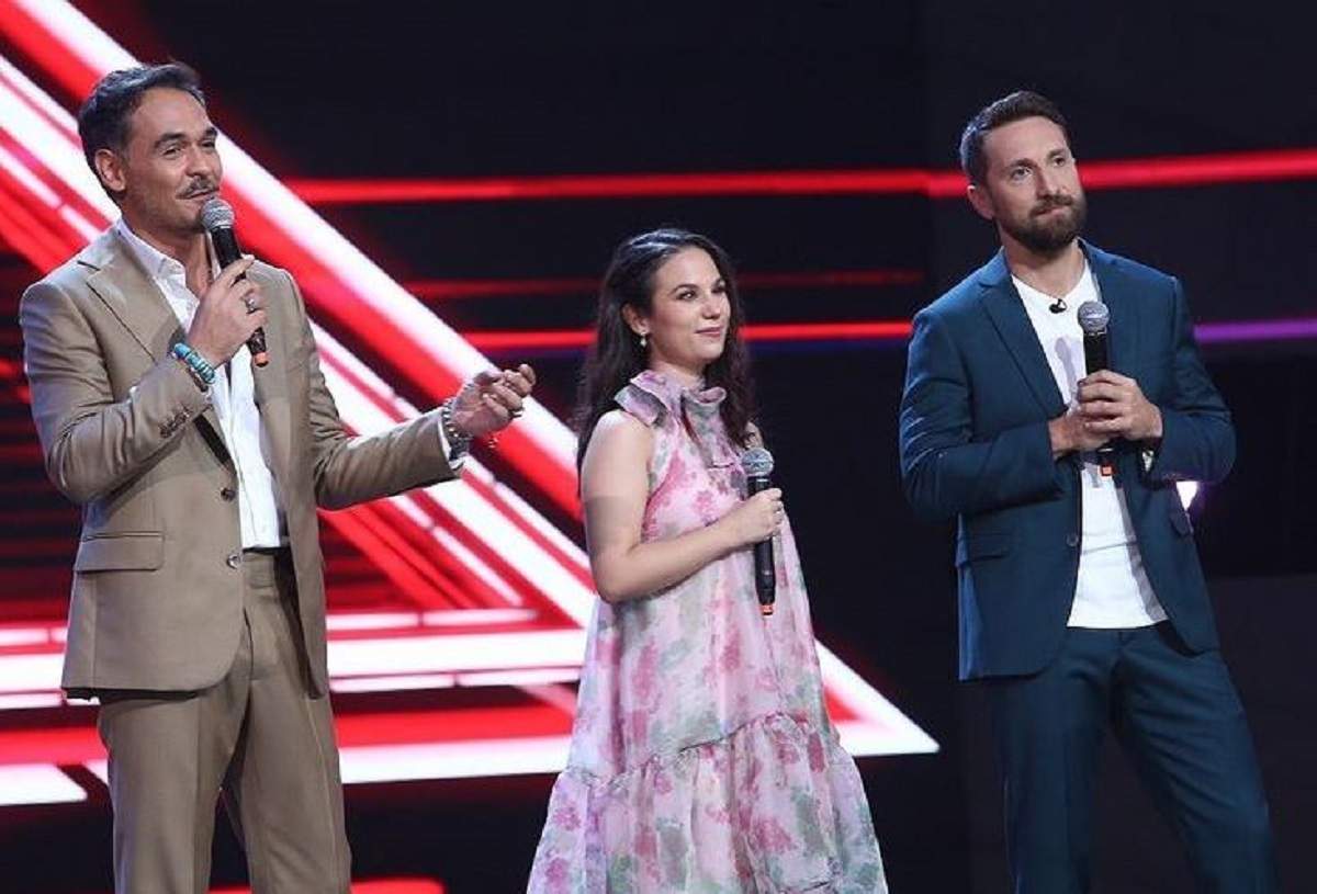 Andrada Precup se află la X Factor. Pe scenă sunt și Dani Oțil și Răzvan Simion. Ea poartă o rochie înflorată.