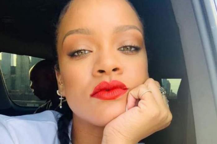 Rihanna se află în mașină. Artista poartă un tricou alb și este dată cu ruj roșu pe buze. Cântăreața își susține fața în palmă.