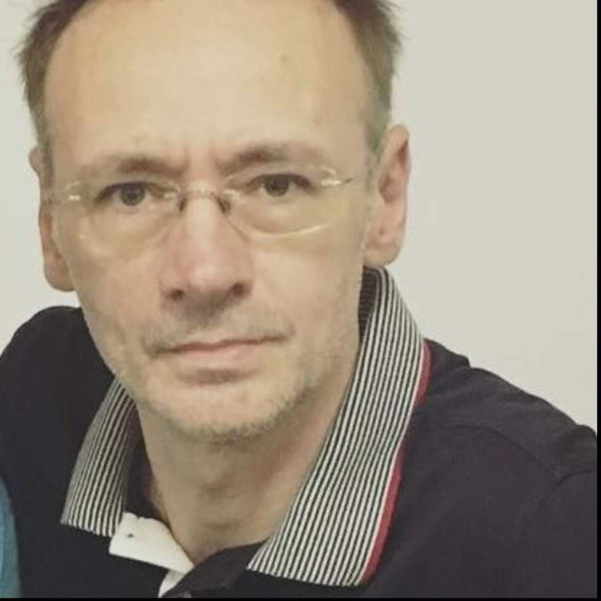 Mihai Albu poarta un tricou negru cu un guler cu model, poarta ochelari de vedere