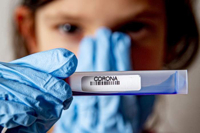 Un test coronsvirus, ținut de un medic în mână, în fața unui copil