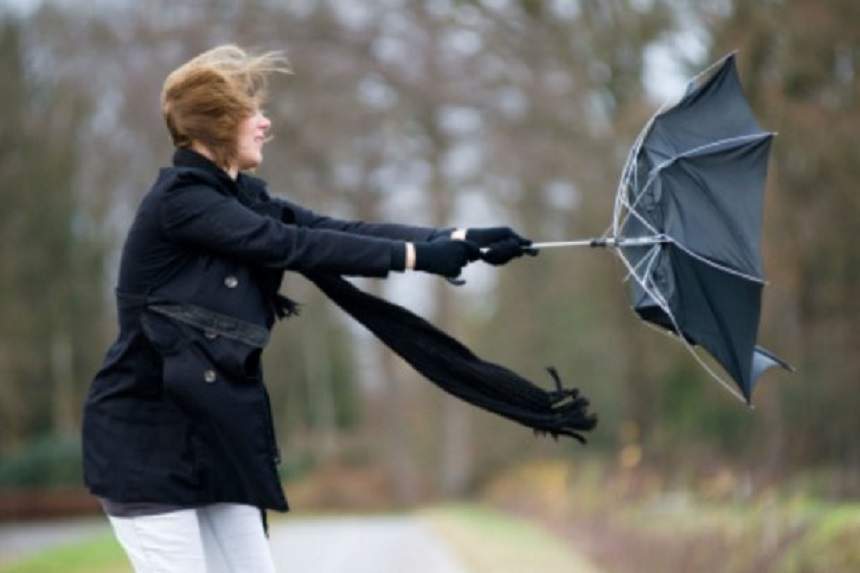 O femeie care ține umbrela, întoarsă de vântul puternic