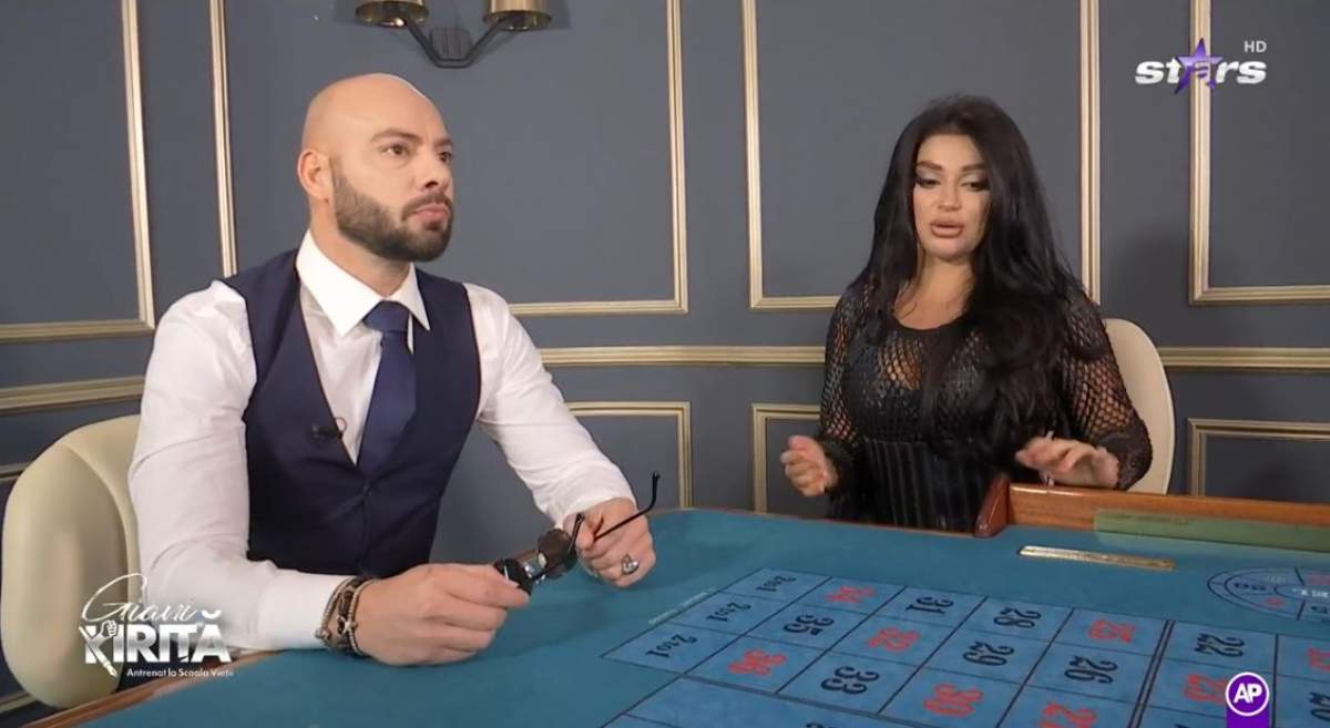 Giani Kiriță și Elena Ionescu stau la o masă. Cei doi se află în casino. Artista poartă o rochie neagră, iar el o cămașă albă, cu vestă neagră.