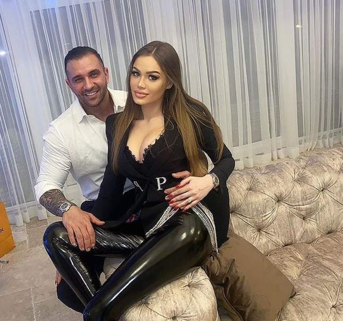 Alex Bodi și iubita lui se află pe canapea. Daria îi stă în brațe afaceristului și amândoi zâmbesc larg.