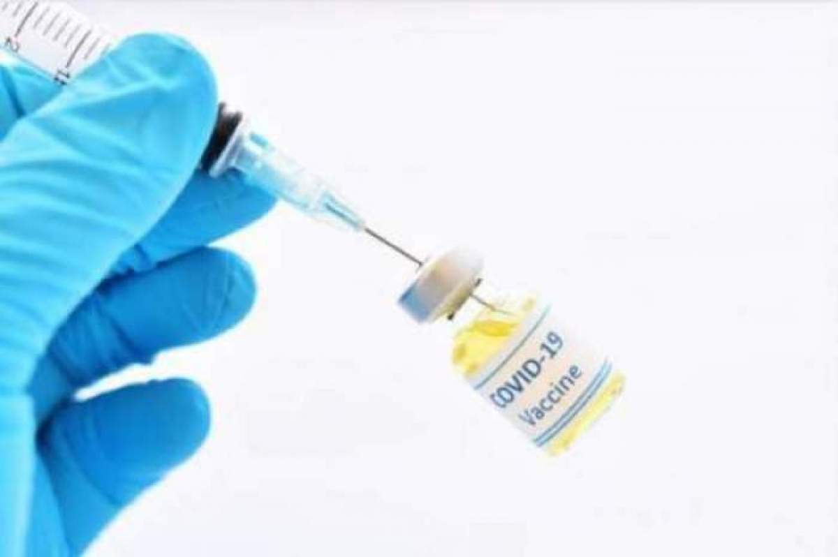 O sticluță de vaccin și o seringă în mâna unei medic