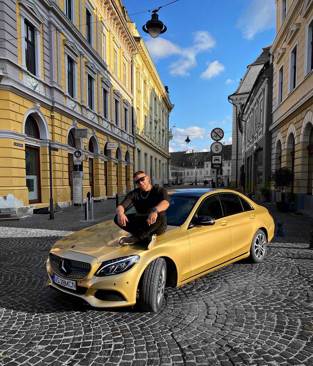 Bogdan Mocanu sta pe masina lui aurie, parcata pe strada