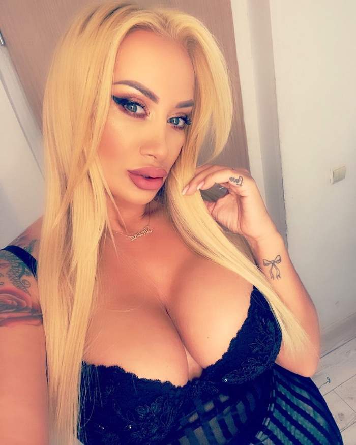 Simona Trasca poarta un top cu bretele negru, cu decolteu adanc, are parul desprins si tine mana la gura