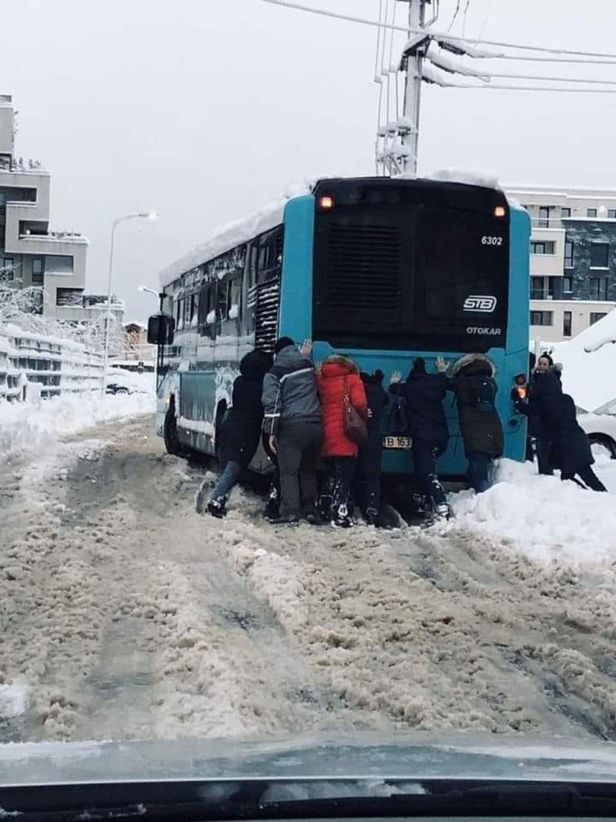 Imaginea zilei! Mai mulți călători împing un autobuz STB, ca să îl scoată din zăpadă