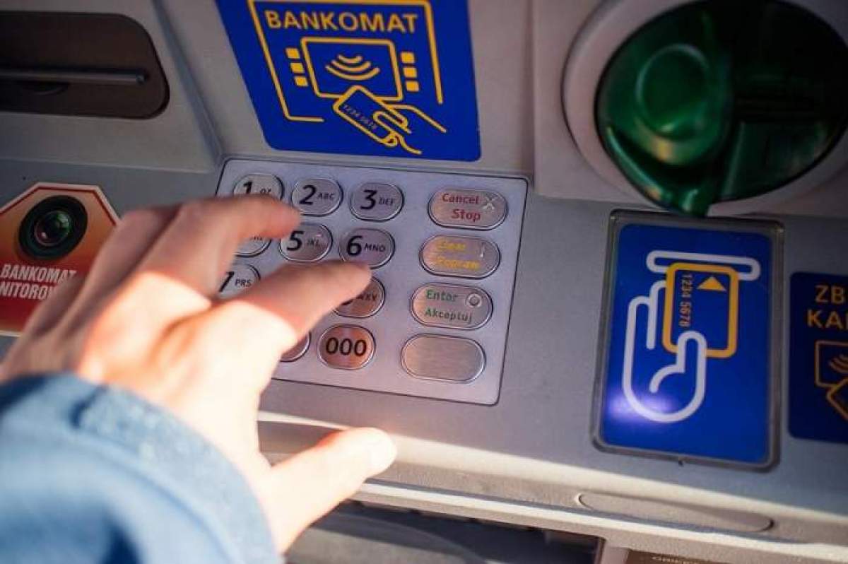 o persoană apasă pe butoanele unui bancomat