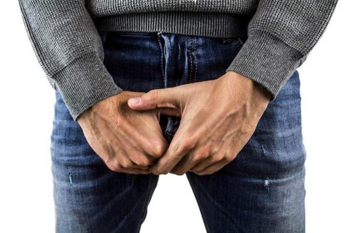 bărbat îmbrăcat cu blugi ţine mâinile în zona genitală